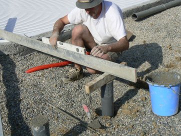 Die Ausrichtung des Betonsockels zur Oberseite des Randsteins wird überprüft.